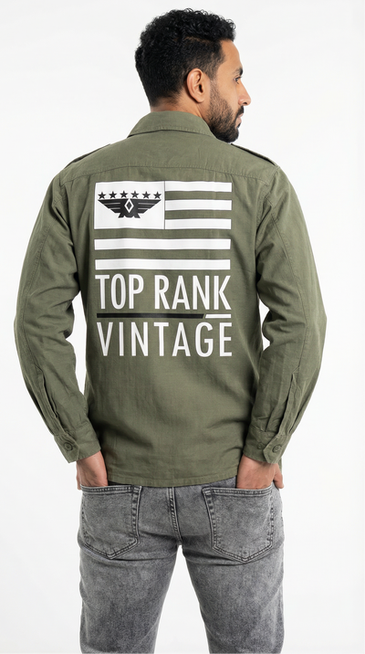 Man wearing a green jacket with text and gray pants on a white background