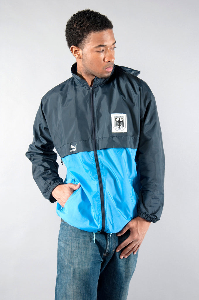 Retro 80s West German Puma windbreaker with German Army emblem, rollable hood, water-repellent, in blue and black.