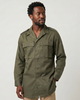 Man wearing a green hbt cotton twill mlitary shirt on a white background