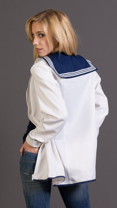 Woman wearing a white british royal navy cotton vintage shirt with blue accents and brown boots against a gray background