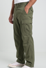 A person wearing olive green cargo pants with side flap pockets, paired with a white t-shirt and white low-top sneakers, shown from the waist down against a light gray studio background.