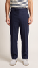 A person wearing navy blue straight-leg wool flap-style pants and navy and white striped shirt, and white shoes, shown from the waist down against a light beige studio background.