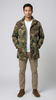 Man wearing a camouflage jacket, white shirt, beige pants, and brown shoes on a white background